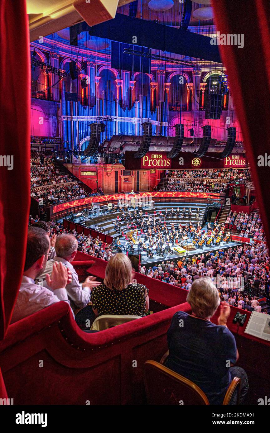 ALBERT HALL INTERIOR BBC PROMS Performance with audience applauding clapping Sheku Kanneh-Mason British cellist, taking a bow, elevated view from luxury red velour private box to audience and orchestra stage dais behind London UK Stock Photo