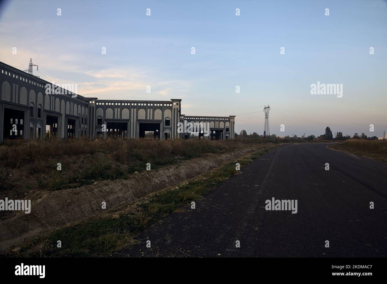 Empty road with abandoned warehouses and pylons at sunset Stock Photo ...