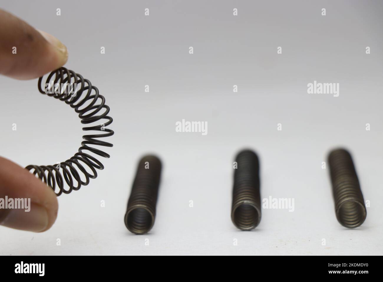Hand compressing and bending a metal coil compression spring with same