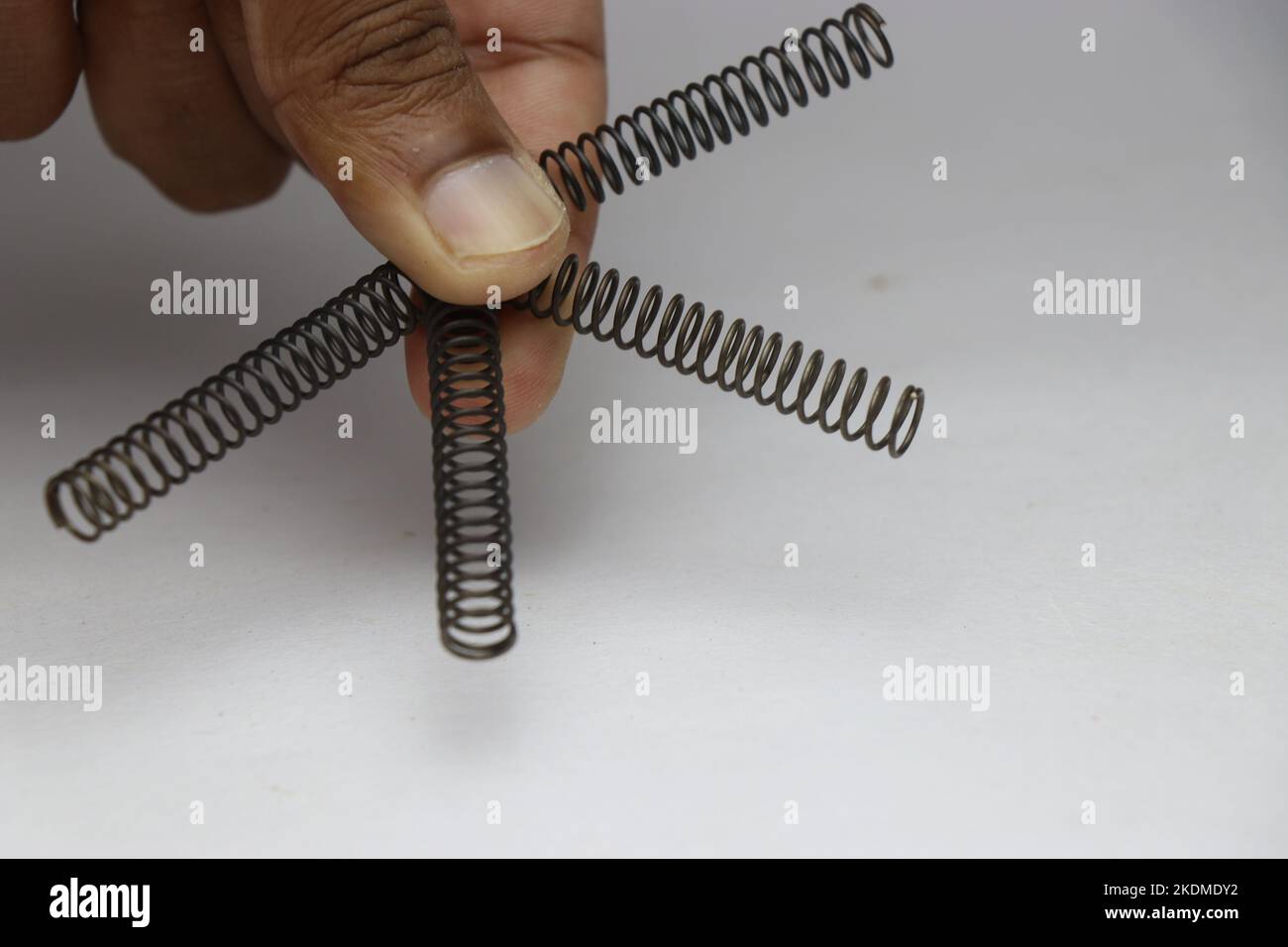 Hand holding four compression springs made of metal that is used on