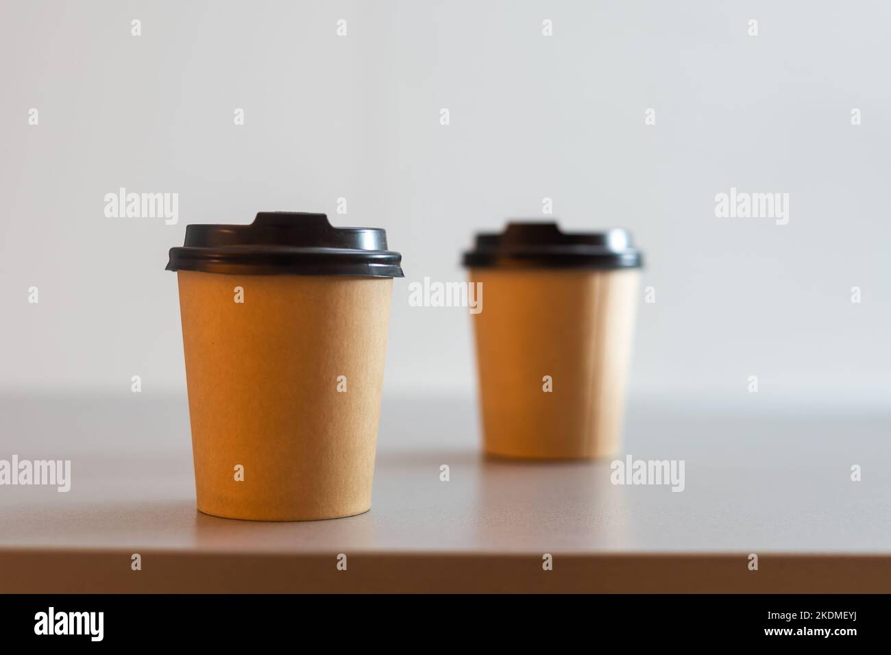 paper cups side by side stay on brown background Stock Photo - Alamy