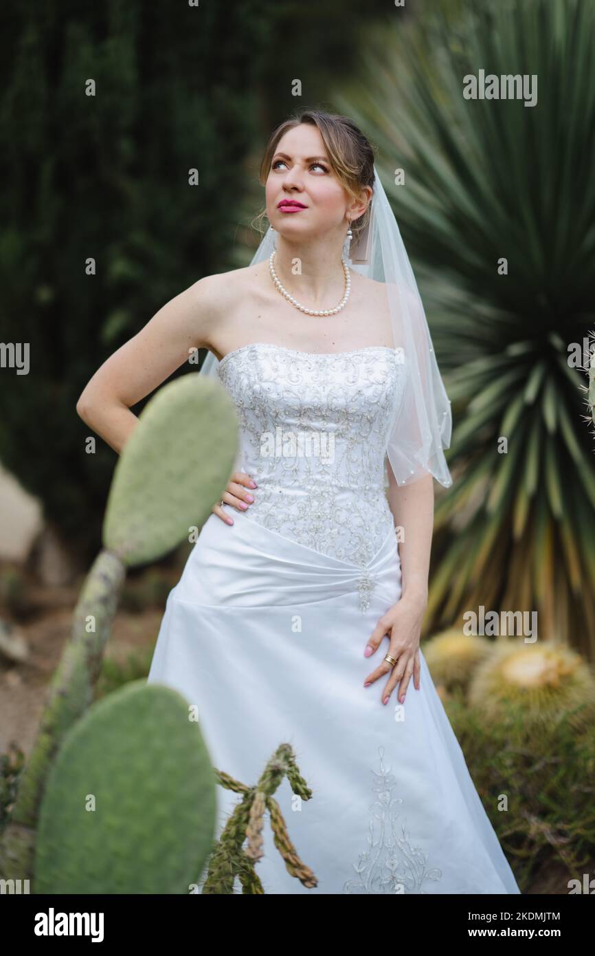 Bride Surrounded by Cactus Plants in a Garden During the Late Afternoon Stock Photo