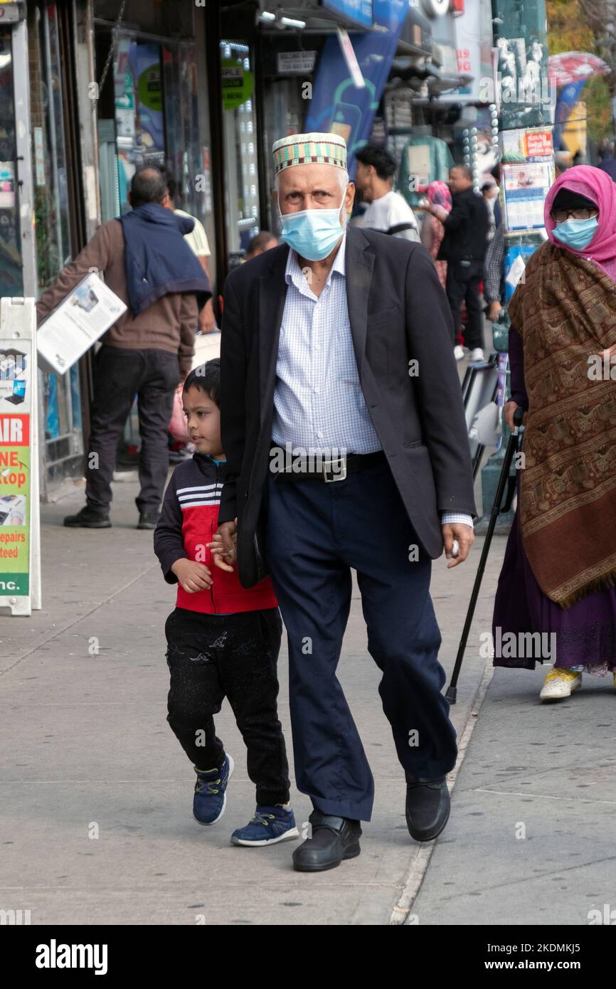 A grandfather & grandson walk hand in hand through Diversity Plaza in Jackson Heights, Queens, New York City. Stock Photo