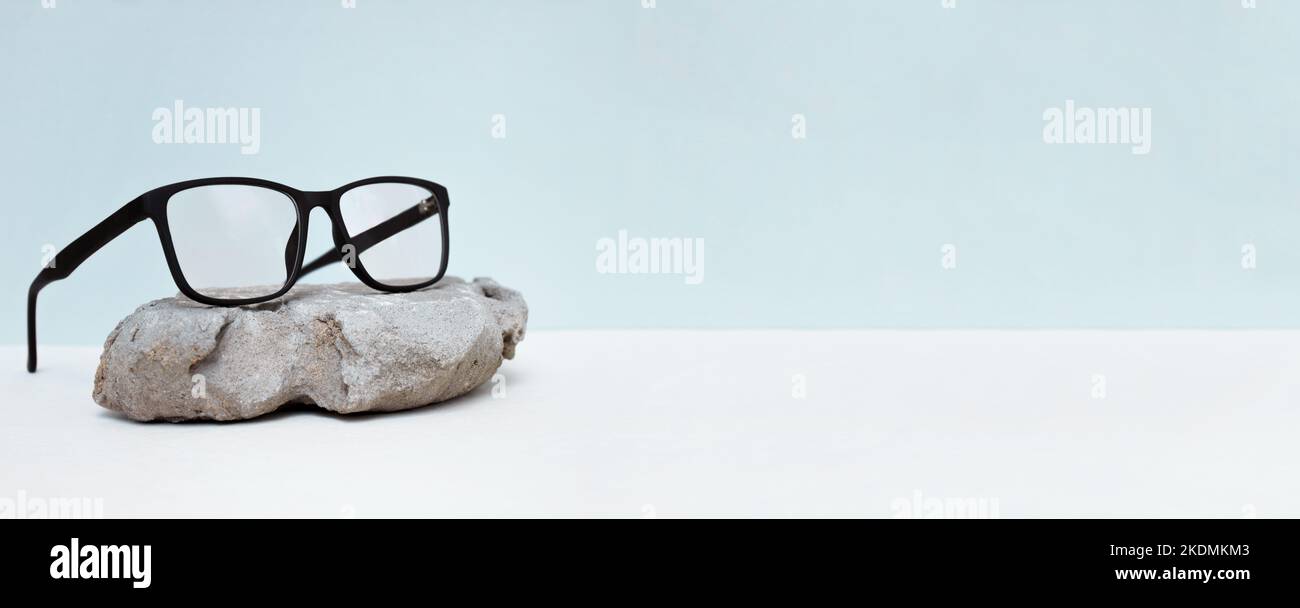 glasses on blue background with stone. glasses sale concept. Copy space for text. Optic store discount poster. Banner Stock Photo