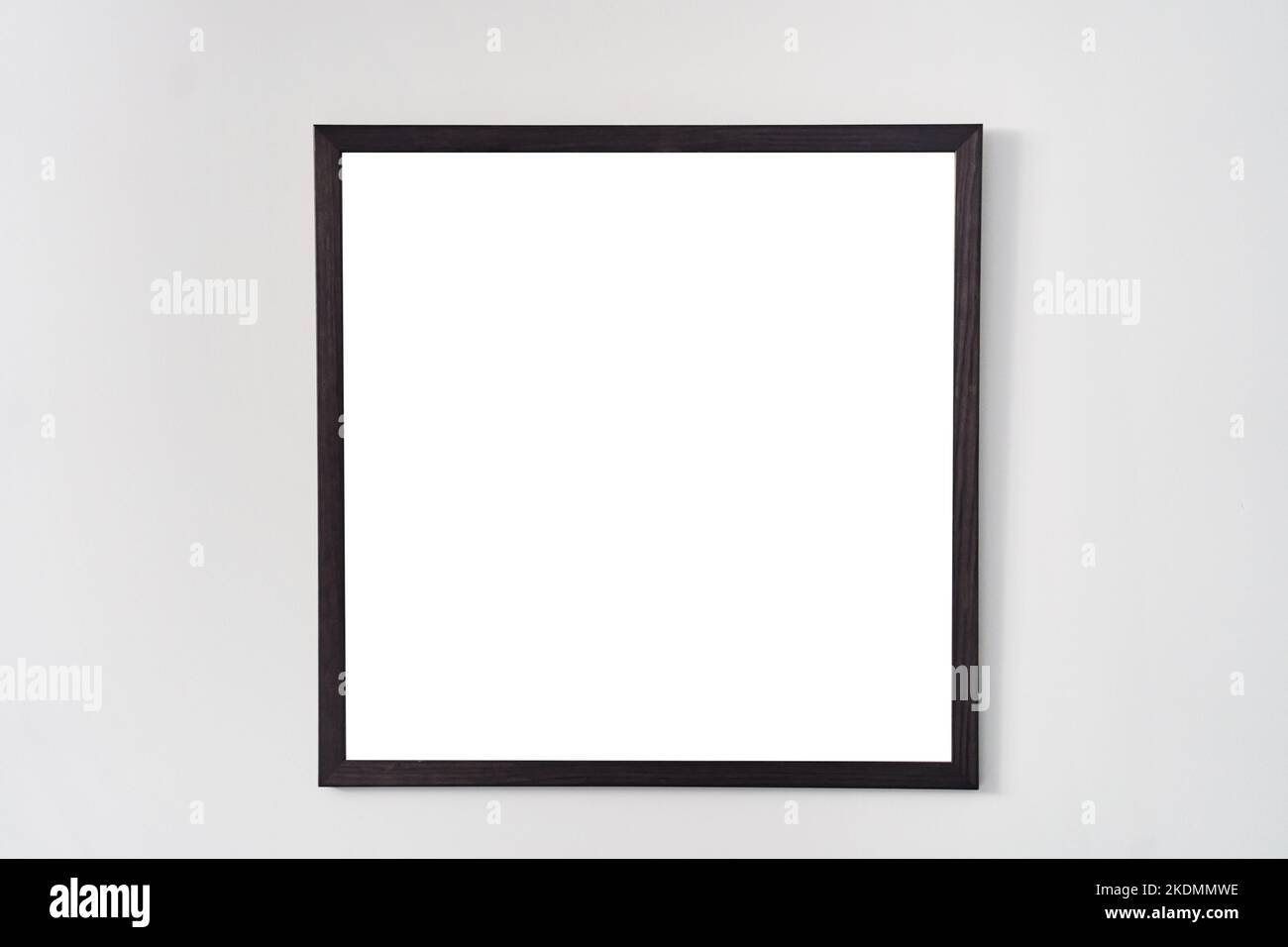 An empty square photo frame with a black border hanging on a white wall Stock Photo