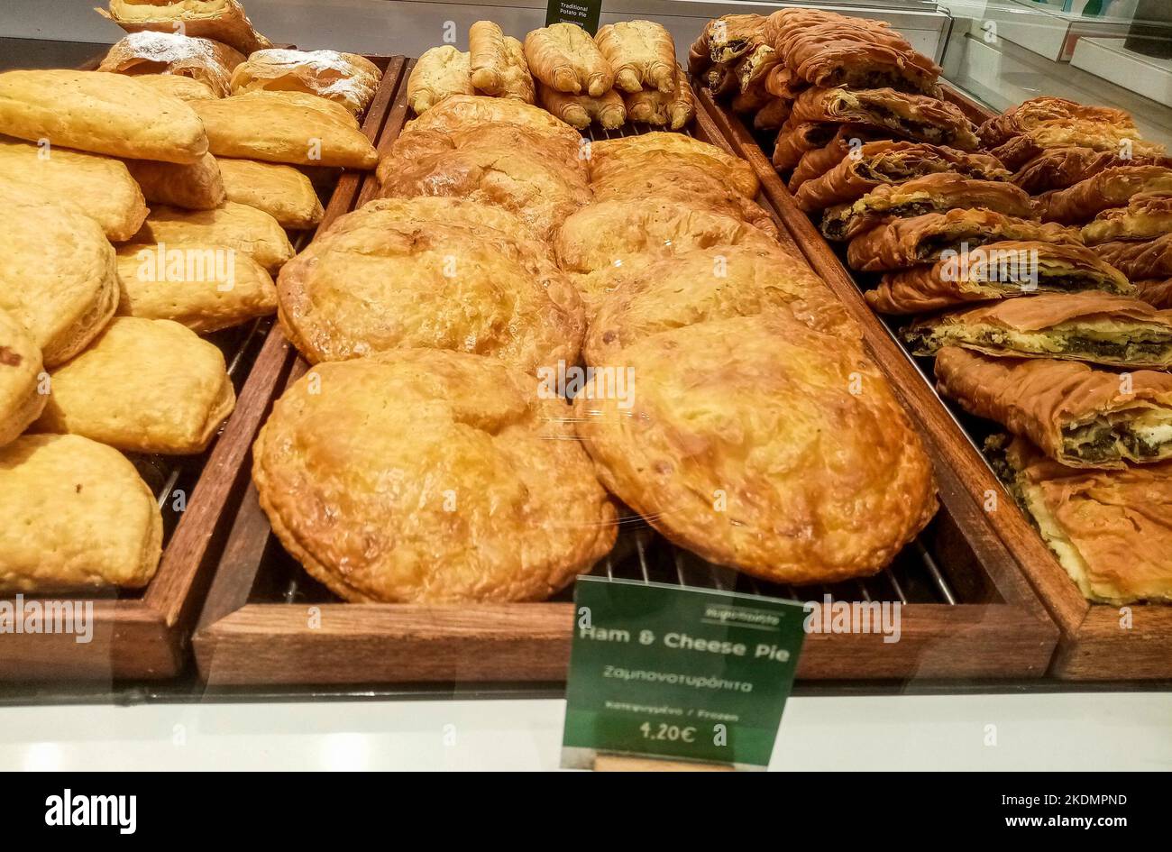 Freshly baked Greek spinach pie and ham cheese pie lined up for sale in a Greece local food shop. Stock Photo
