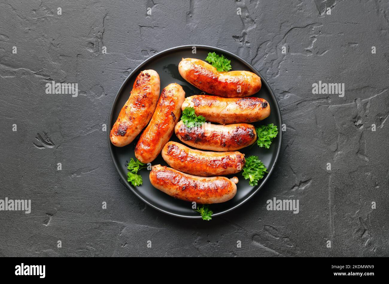 Barbecue bratwurst on plate over dark stone background.  Top view, flat lay Stock Photo