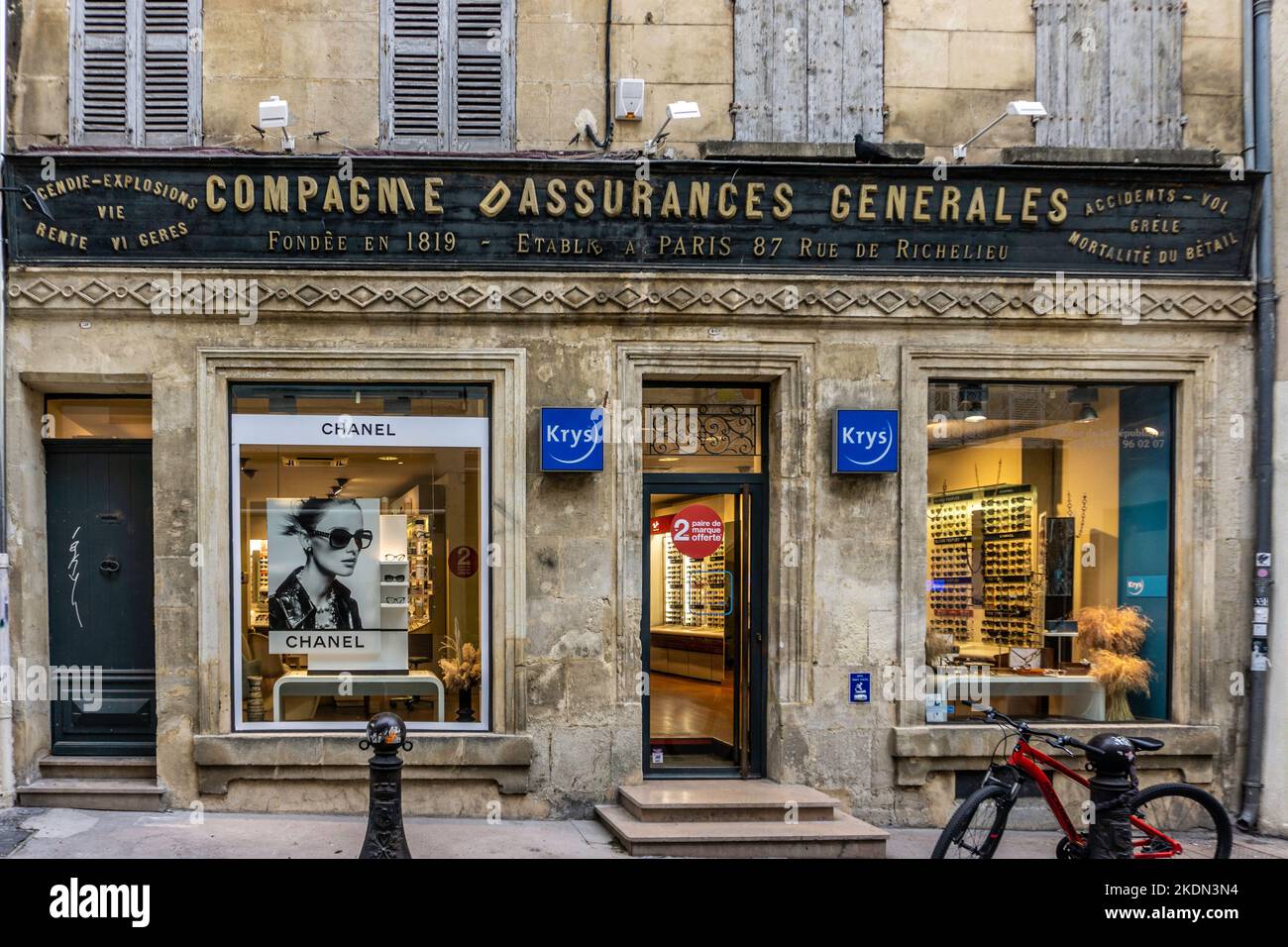 A branch of Kris Optician in Arles, France. Located in an historic building whose original sign has been preserved. Stock Photo
