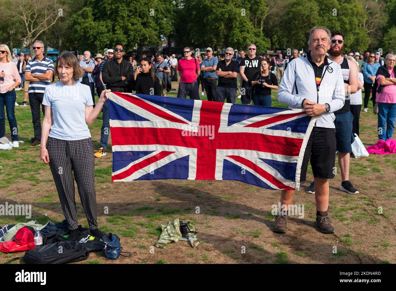 A couple holding a Union Jack flag as they watch the live broadcast of Her Majesty the Queen's coffin being taken by military procession from Buckingh Stock Photo