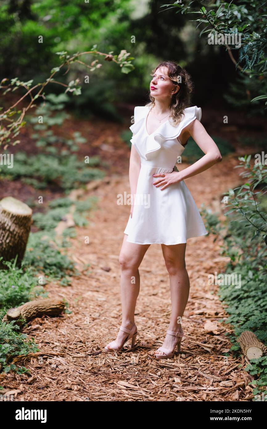 Woman Wearing a Short White Dress Standing on a Garden Path Stock Photo