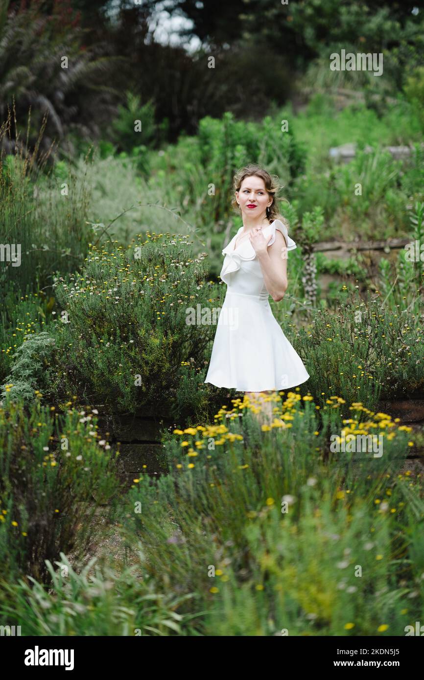 Woman Wearing a Short White Dress Standing on a Garden Path Stock Photo