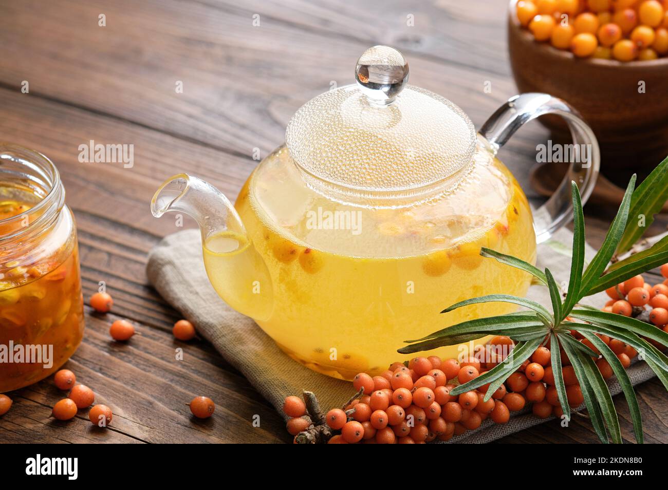 Glass tea kettle of healthy sea buckthorn tea, a sprig of buckthorn