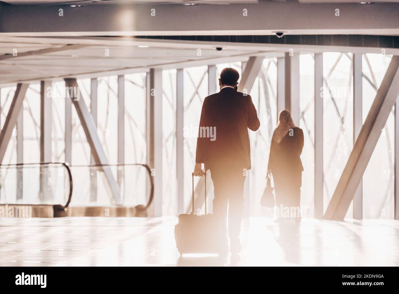 Businessman dragging a small carry on luggage suitcase at airport