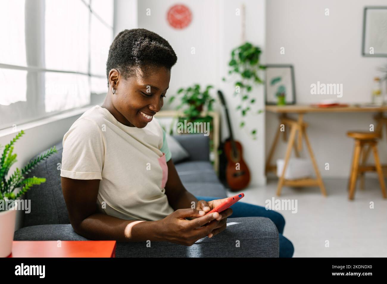 Happy young african american woman relaxing on sofa while having fun ...