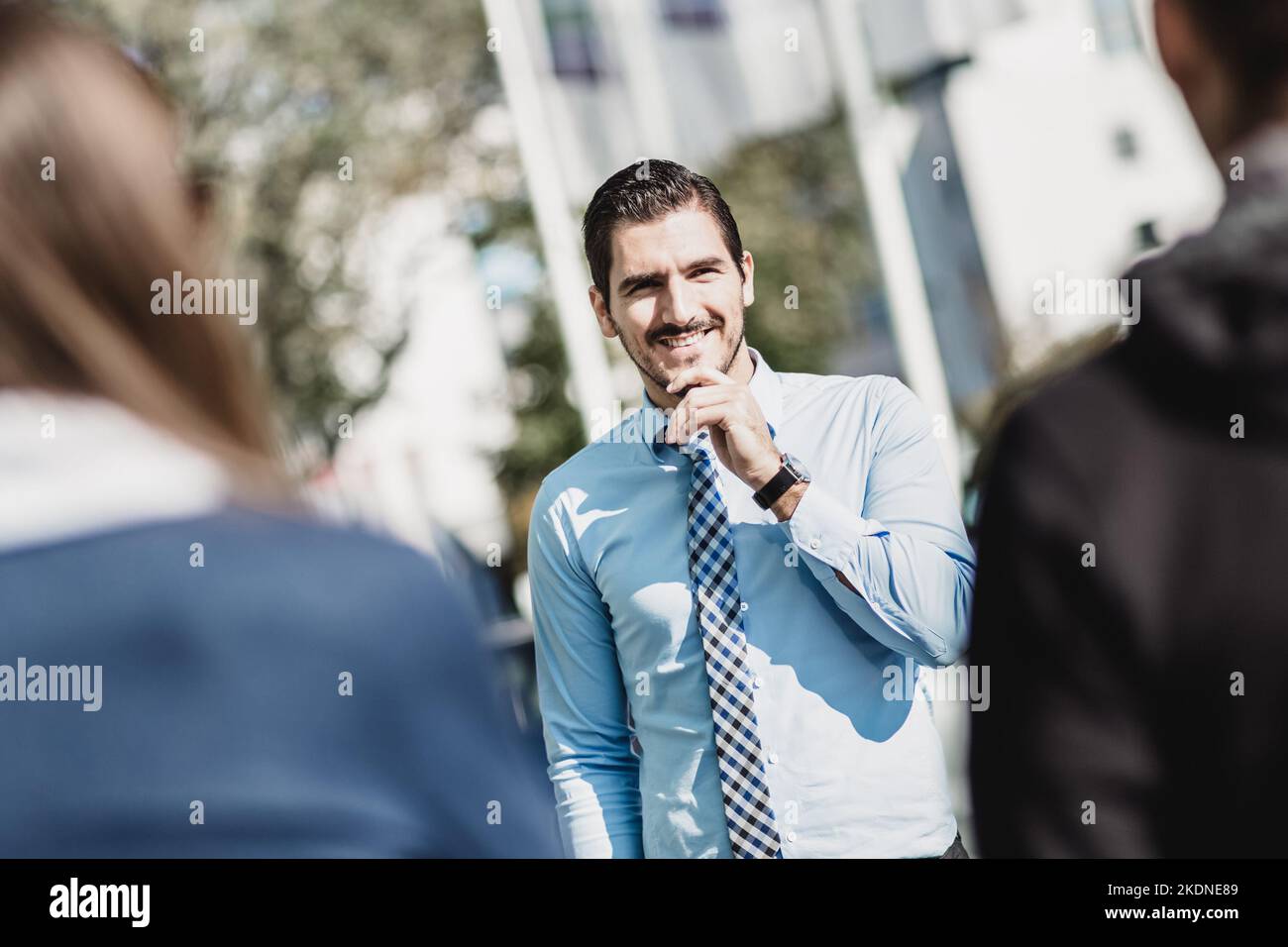 Attractive young businessman with a friendly smile having informal out of office meeting on a suny day. Stock Photo