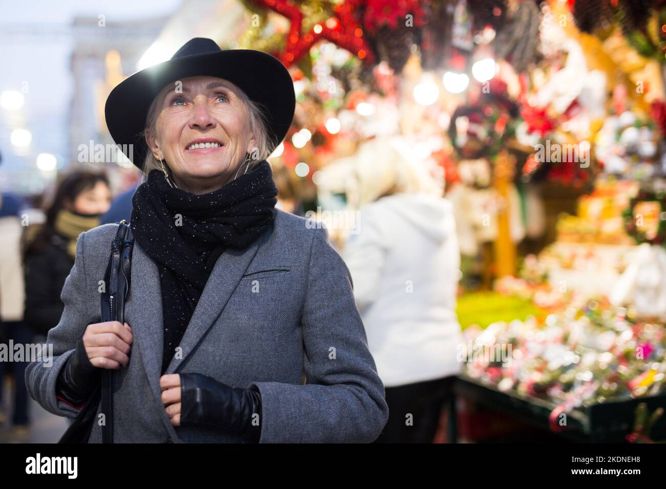 Smiling aged woman walking at traditional city christmas fair Stock Photo