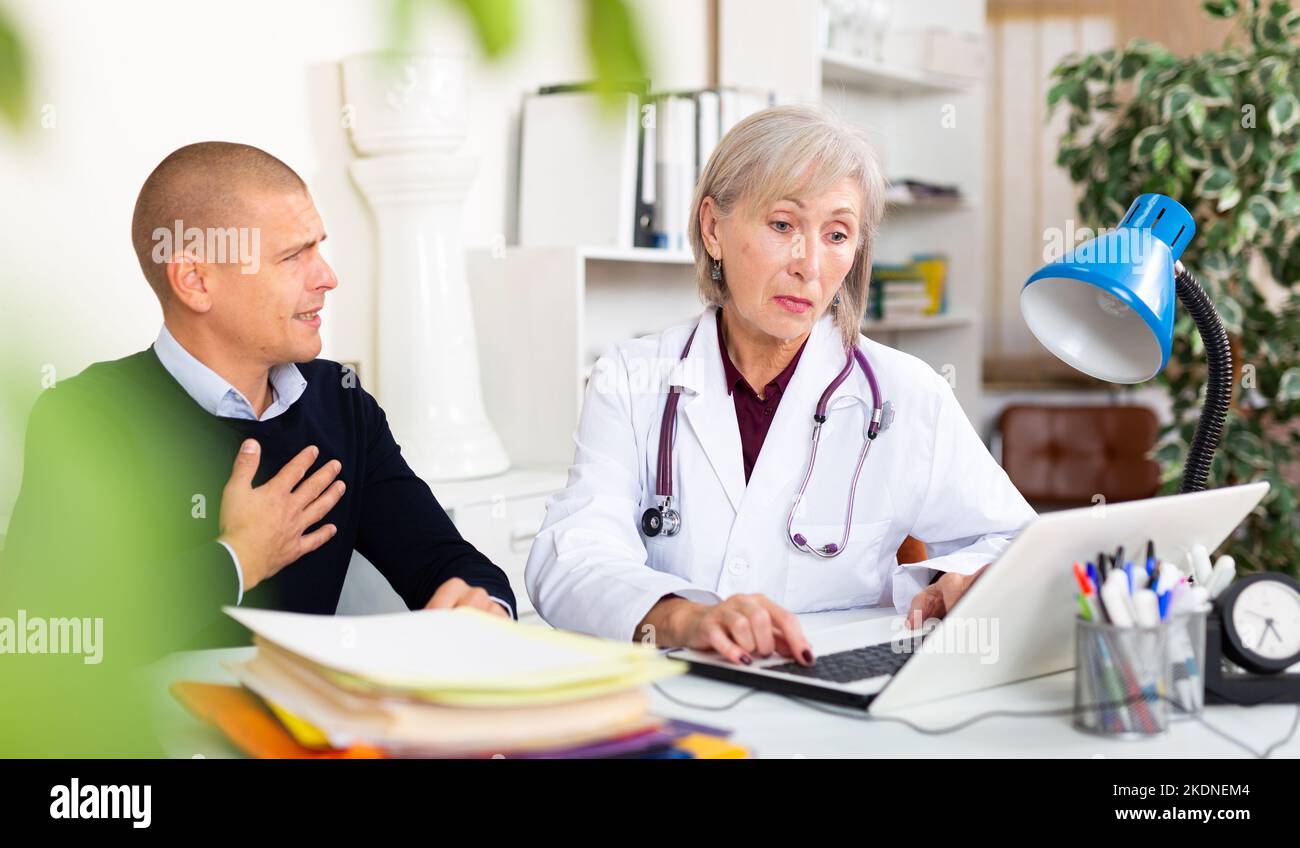 Man complaining about cardialgia to senior woman physician Stock Photo
