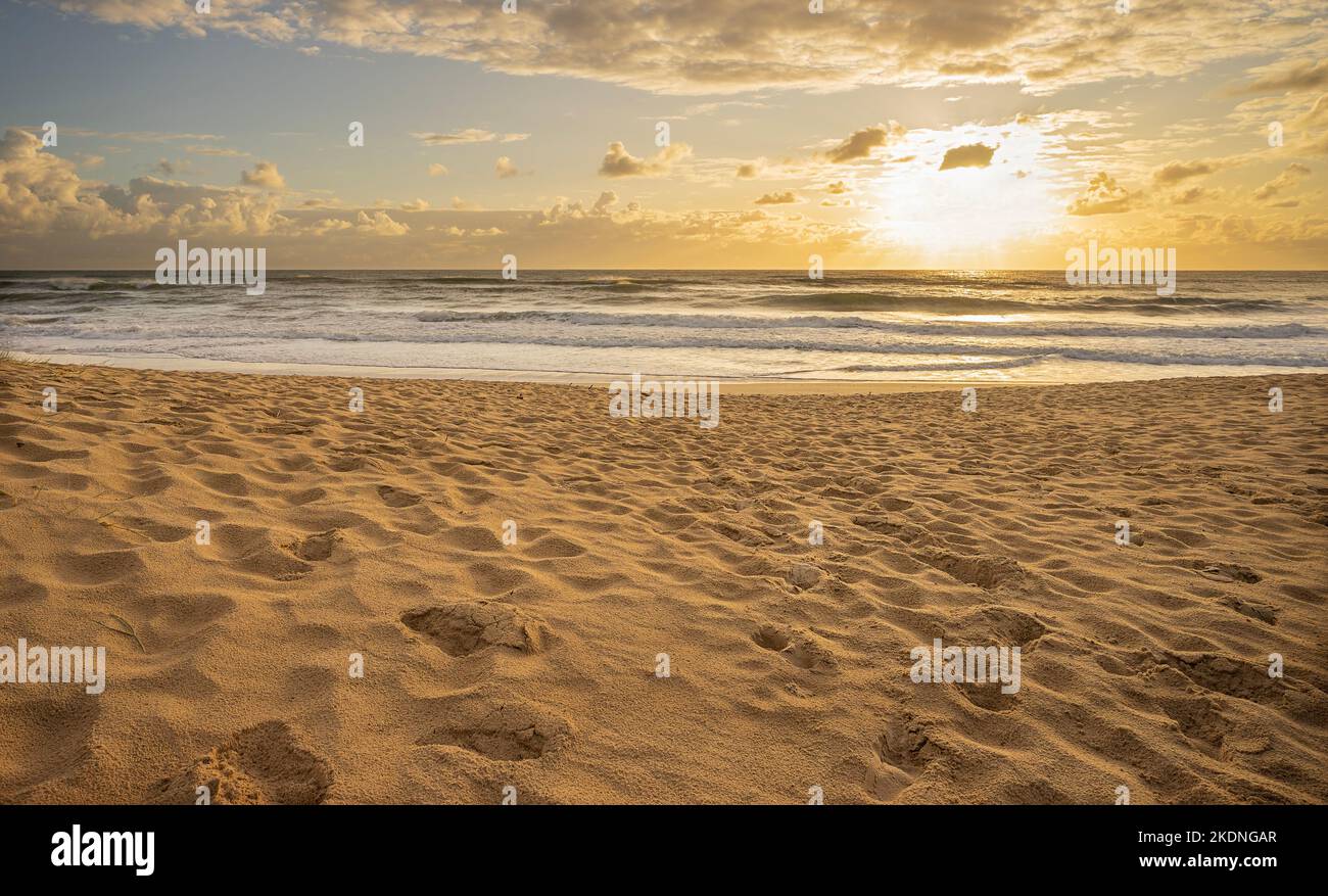 Sunrise over Pacific Ocean at Cotton Tree, Maroochydore, Sunshine Coast. The surf is rough and the tide coming in onto a sandy beach with lots of foot Stock Photo