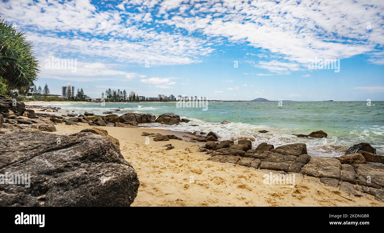 Scene looking north from Alexandra Headland on the beach towards Cotton Tree on Sunshine Coast, Queensland. Rocky headland, rough sea, and blue sky wi Stock Photo