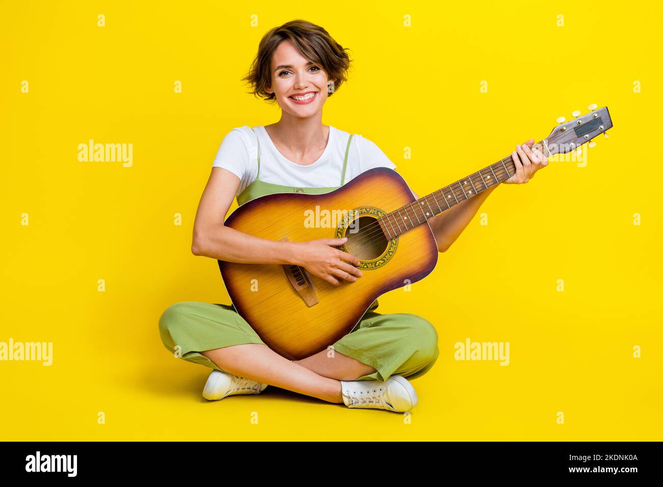 Full body photo of cute young woman learning playing guitar crossed