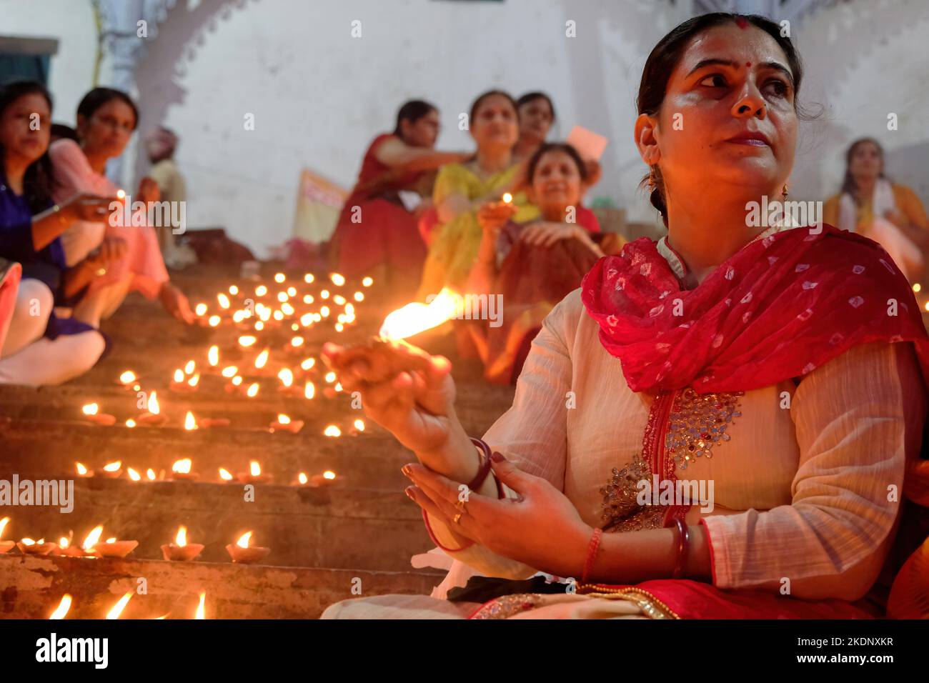 A woman performs rituals during the occasion. Devotees are lighting oil