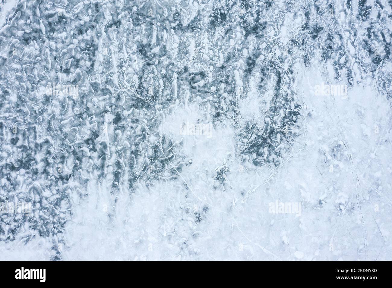 frozen lake ice texture covered with snow. human footprints on ice