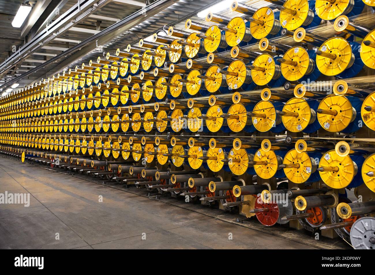 Bright yellow spools on shiny metal rods in plant Stock Photo