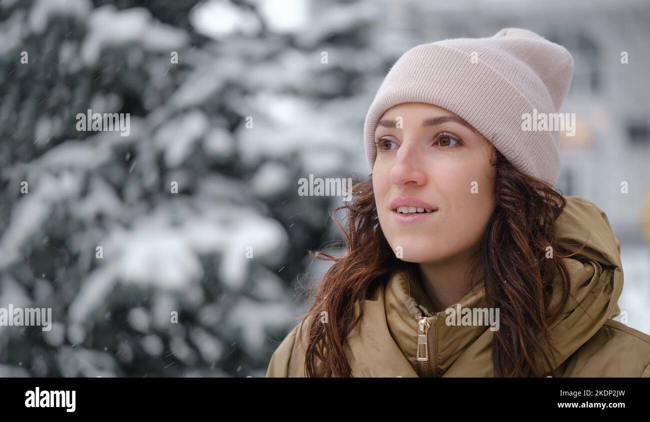Happy middle age woman catching snowflakes in the city outdoors. Relaxed emotional person walking in winter urban area in a moment, slow living Stock Photo