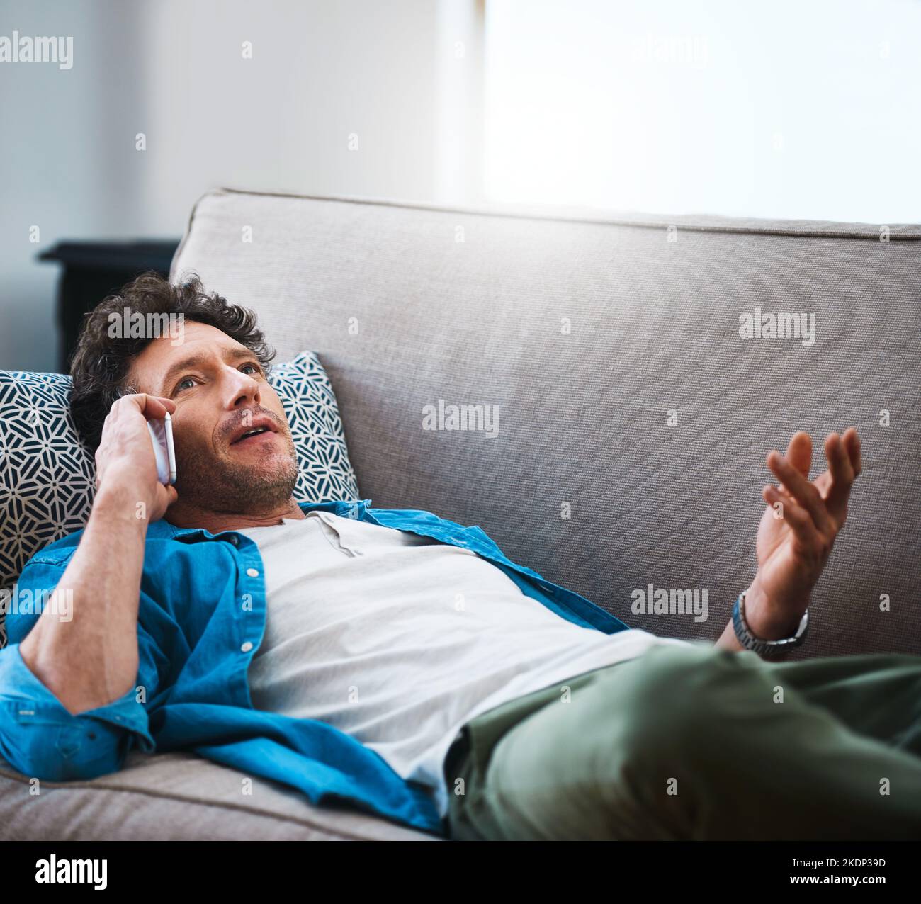 Where did you even get my number. a bachelor answering his cellphone while relaxing on the couch at home. Stock Photo