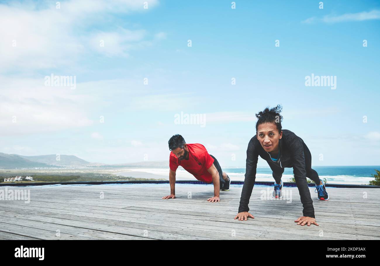 Strengthening those core muscles. a couple doing pushups Stock Photo