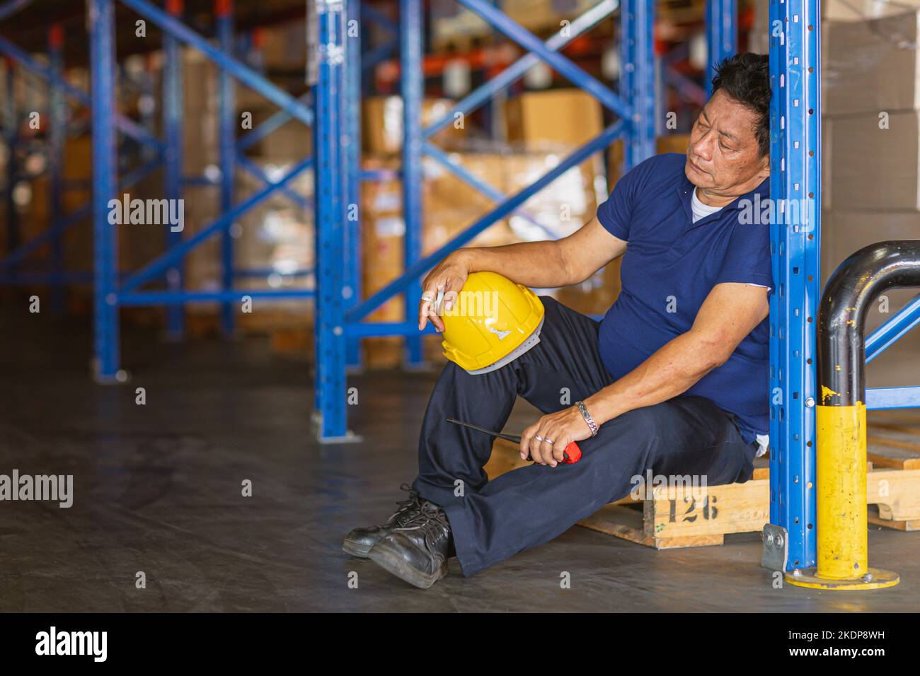 fatigue senior adult worker napping sleep at work exhausted. warehouse industry employee sleeping tired from hard working. Stock Photo
