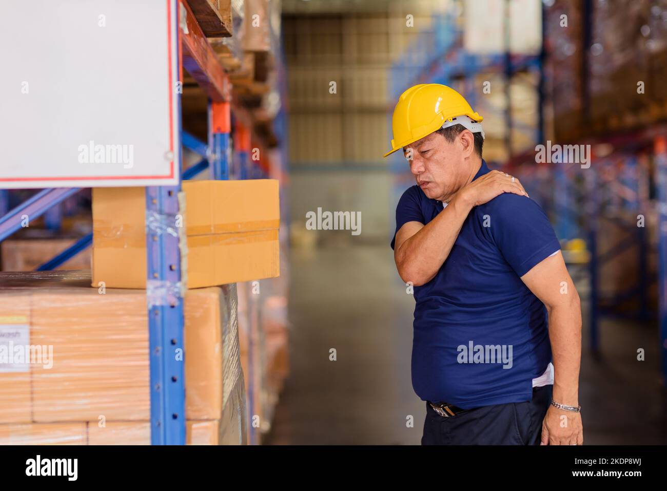 warehouse worker back shoulder muscle pain injuries from heavy lifting hard working. Stock Photo