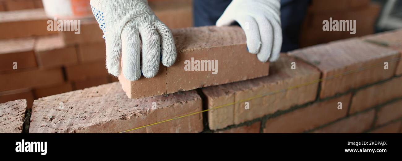 Male builder hands making make brickwork using red bricks Stock Photo