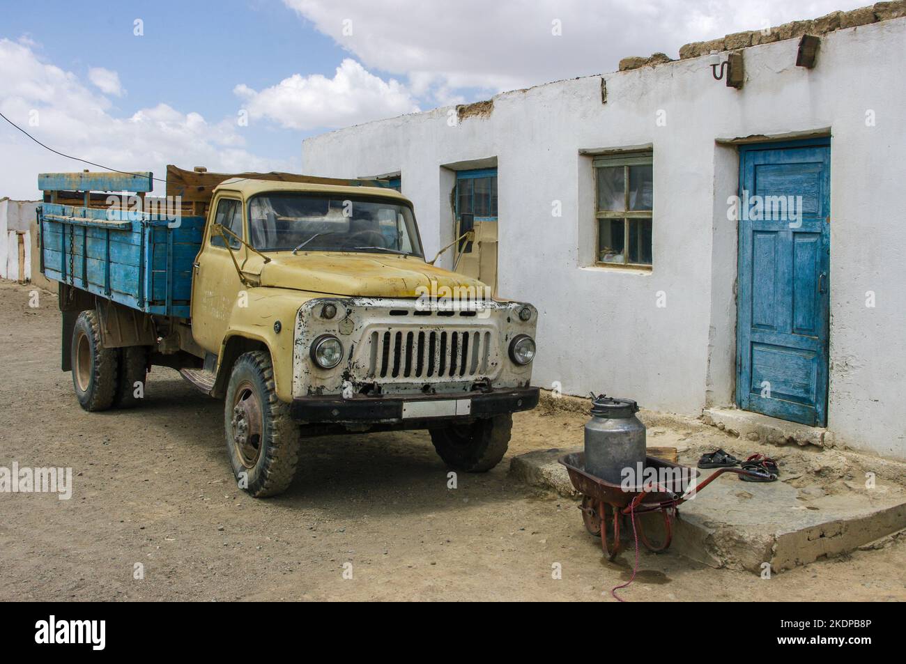 Old vintage soviet era truck with wheelbarrow and milk can in high