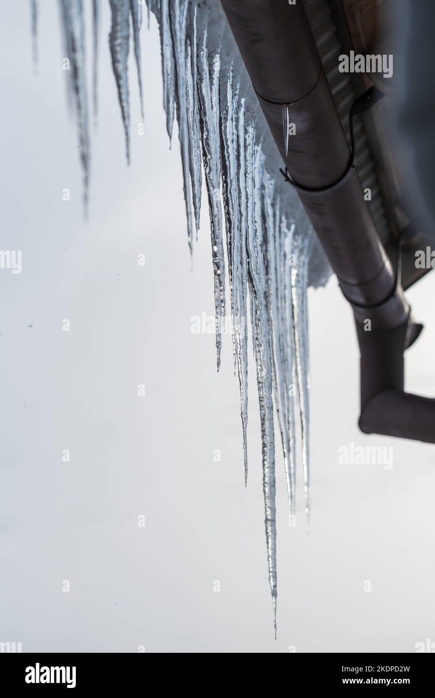 Long and dangerous icicles hanging from roof of house. Stock Photo