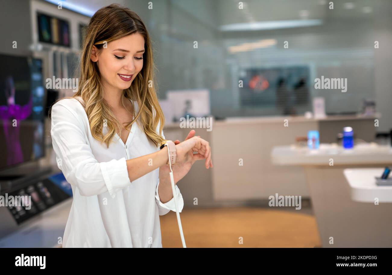 Portrait of happy smiling woman shopping a new smart watch in tech store. Technology people concept Stock Photo