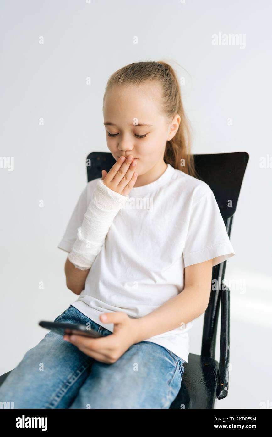 Vertical portrait of cute blonde little girl with broken arm wrapped in