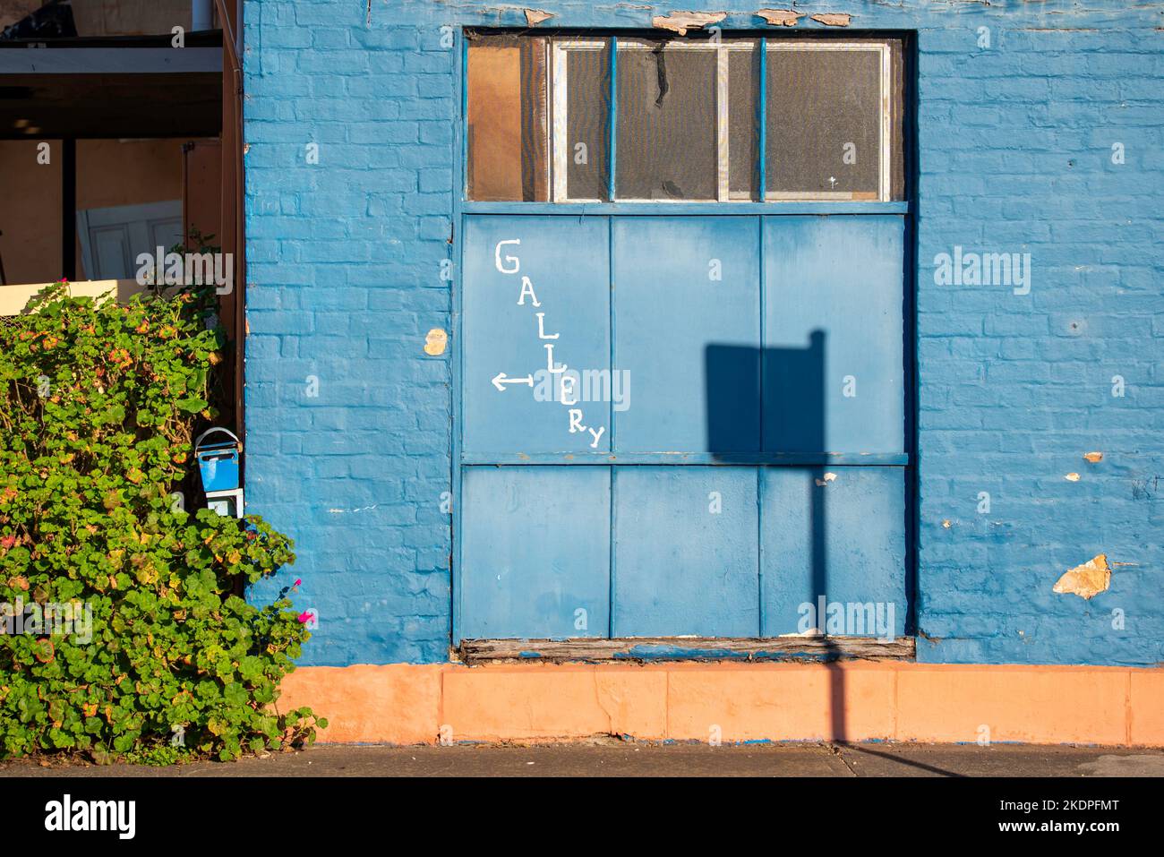 The shadow of a street sign on a blue painted brick wall with a hand