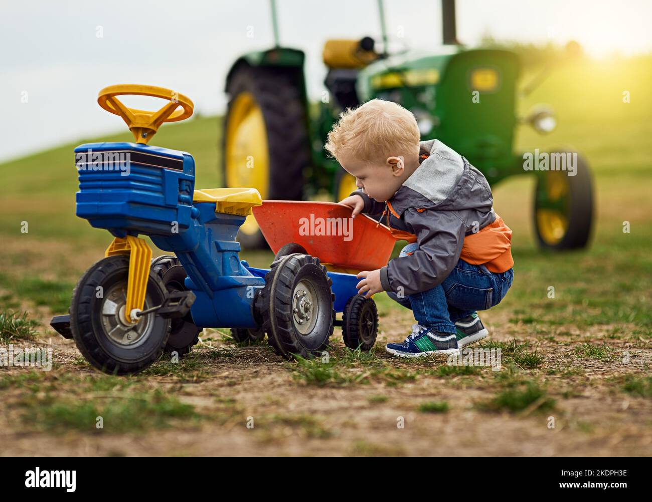 Nothing teaches self sufficiency like growing up on a farm. an adorable little boy playing with a toy truck on a farm. Stock Photo