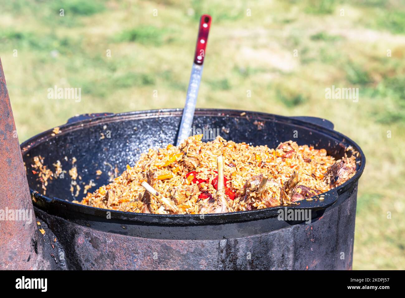 Cooking traditional Uzbek pilaf in a large cauldron outdoors Stock Photo