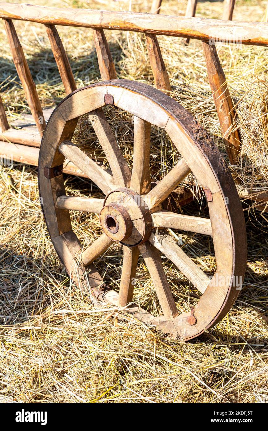 Old wooden farm wagon with traditional wheels made of wood and an rusty iron rim. Vintage wooden carriage wheel with a rusty rim from an old cart Stock Photo