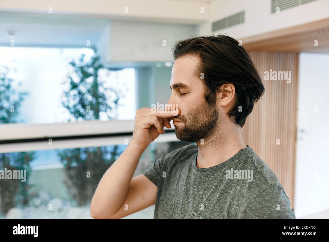 Handsome man practicing yogic breathing technique, pranayama technique and alternating right and left nostril breathing. Yoga breathing exercises Stock Photo
