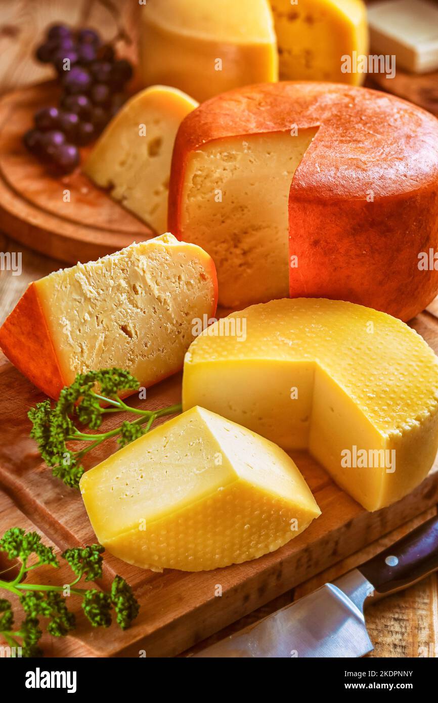 cheese board - still life with various types of cheese, sliced and served loaves of cheeses on cutting boards on table Stock Photo