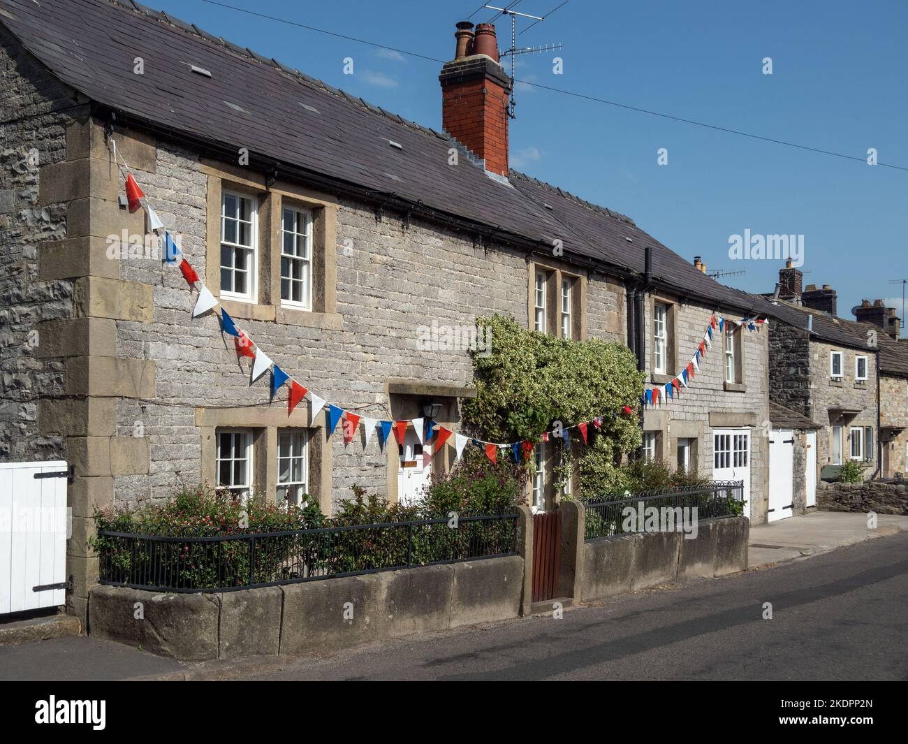 Row of traditional stone built cottages, with bunting, in the pretty village of Ashford In The