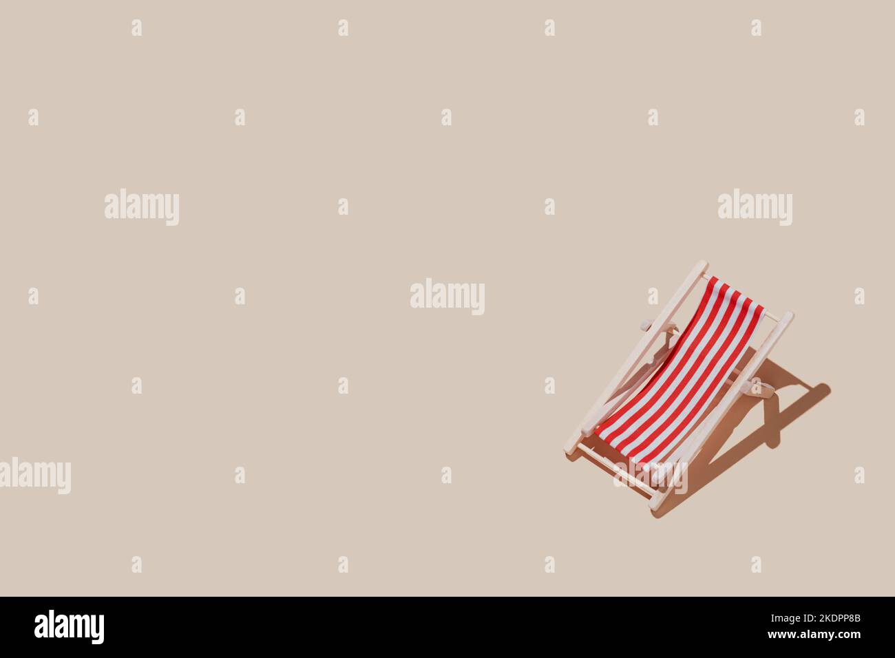 Vacation, beach, travel or relaxation concept. Beige background flat lay as symbol of sand with mini sun lounger for beach chair. Minimalism with copy space area for text, wooden red-white lounge Stock Photo