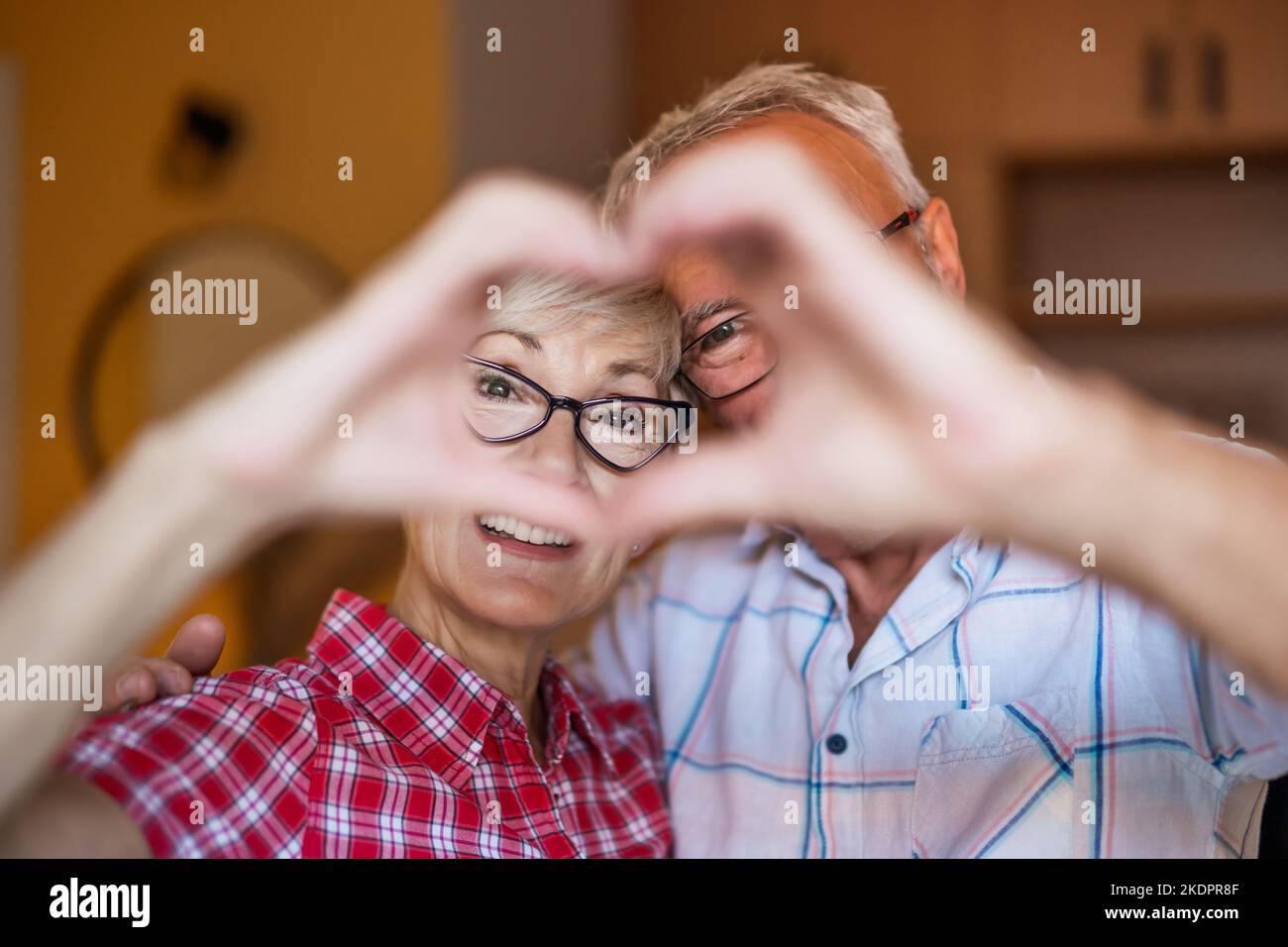 Happy senior couple is embracing and making heart shape with their ...