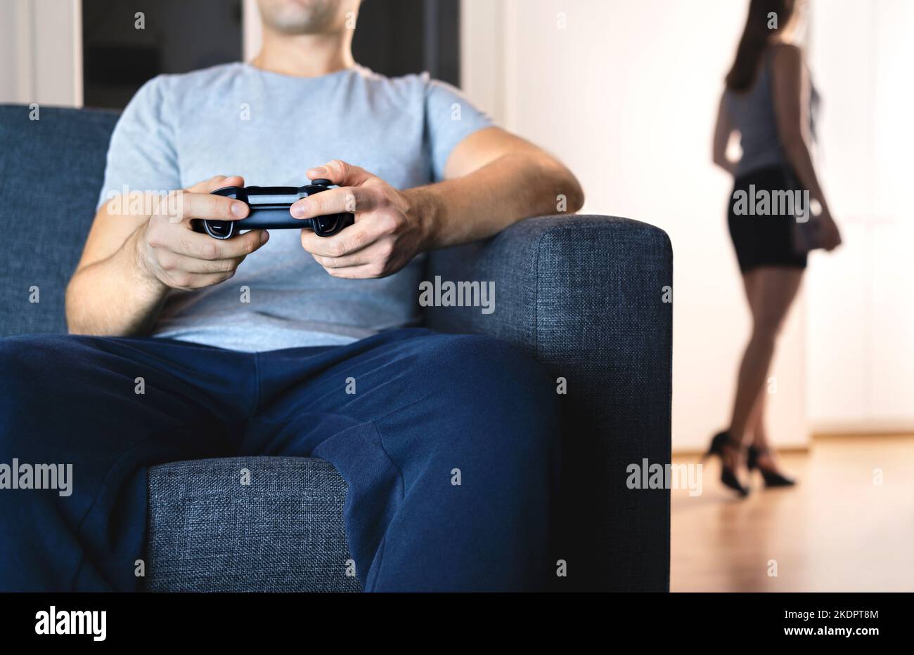 Couple in distant marriage. Man playing video game ignoring woman. Lack of connection. Relationship fight and crisis. Lazy husband on couch. Stock Photo