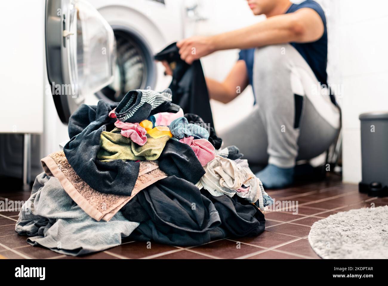 Laundry, washing clothes. Man loading washer machine and sorting by color and fabric.  Male homemaker doing house chores. Domestic work in family. Stock Photo