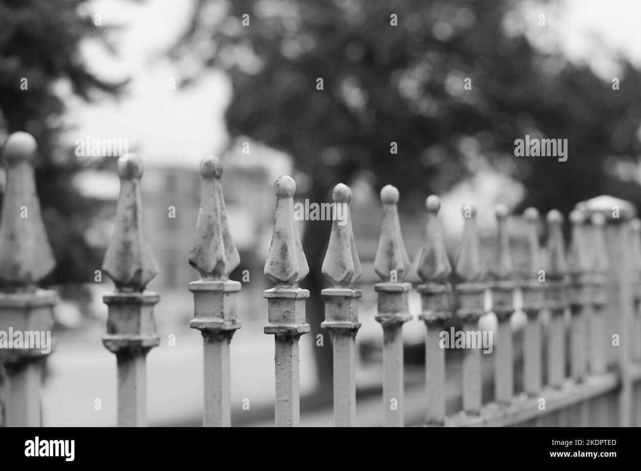 Vintage rusty metal fence with a row of decorative finials in a black