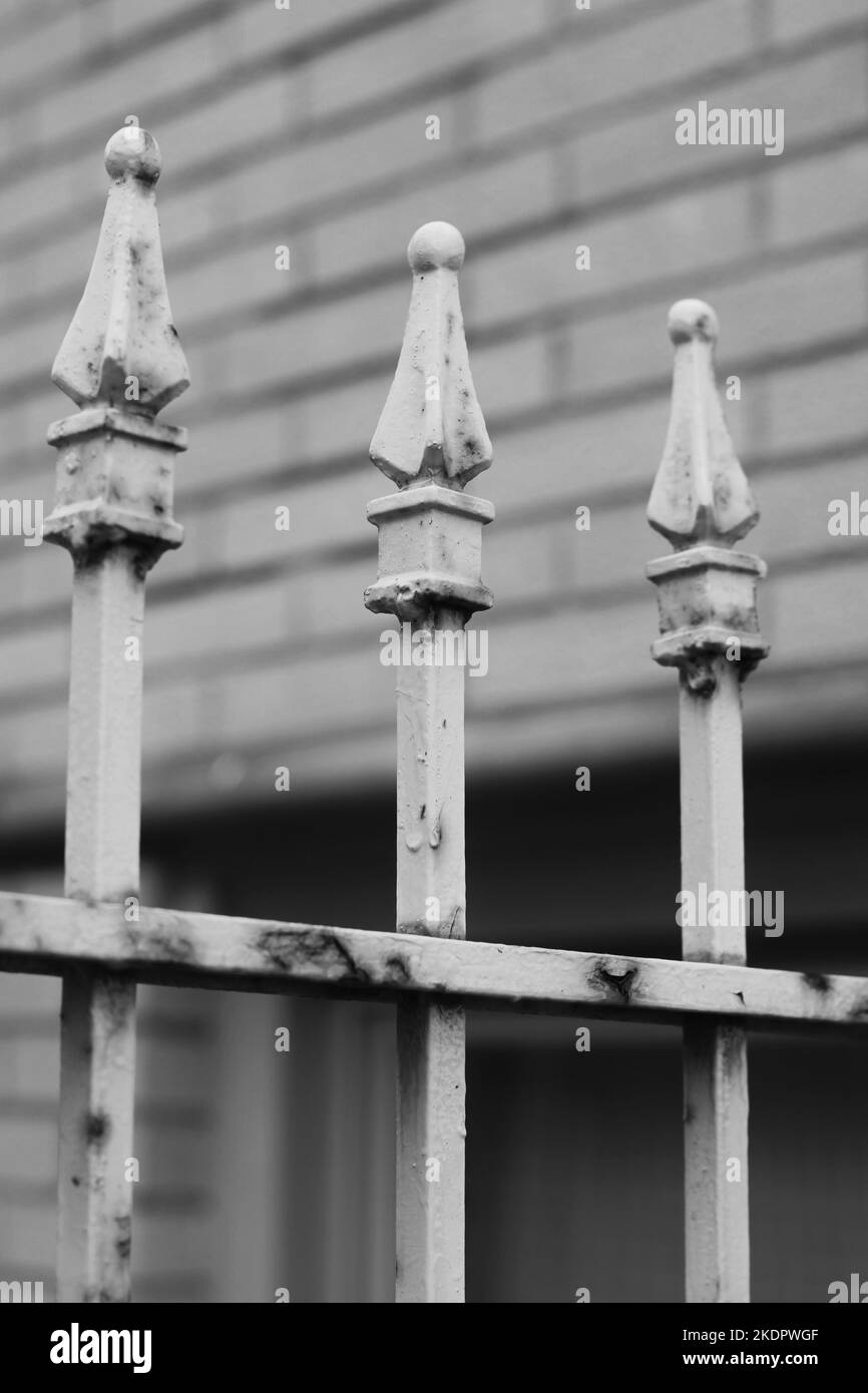 Vintage rusty metal fence with a row of decorative finials in a black